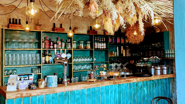 The turquoise bar at Curious Cafe and Bistro on Bath Road, Cheltenham, with dried flowers hanging above