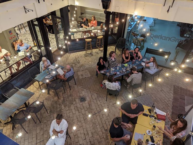 Diners at tables under festoon lights in the courtyard at Sam's Montpellier, Cheltenham