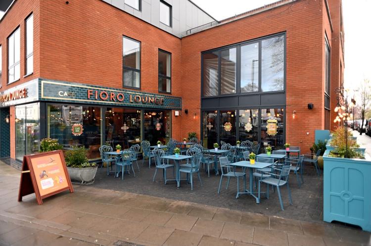 Blue café tables and chairs on the paved terrace outside Fioro Lounge on Bath Road, Cheltenham