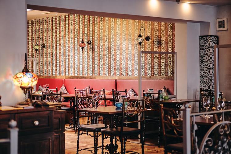 Red banquettes, patterned wallpaper and Turkish mosaic lamps in the dining room of The Istanbul Kitchen, Cheltenham