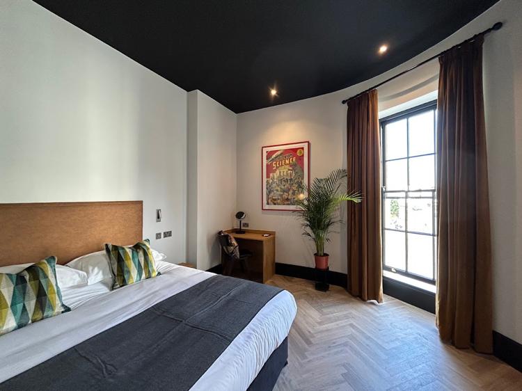A bedroom at Crescent Place by Mansley, Cheltenham, with a tall window and long curtains