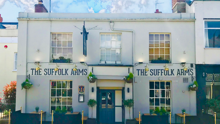 The white front of The Suffolk Arms on Suffolk Road, Cheltenham, with hanging baskets