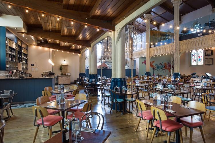 Pink chairs, pillars and a timber roof in the converted church dining room at Zizzi, Cheltenham
