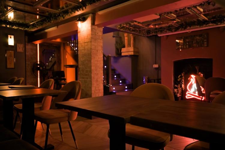 Low-lit tables and a neon flame in the fireplace at 33 The Rum Bar on Prestbury Road, Cheltenham